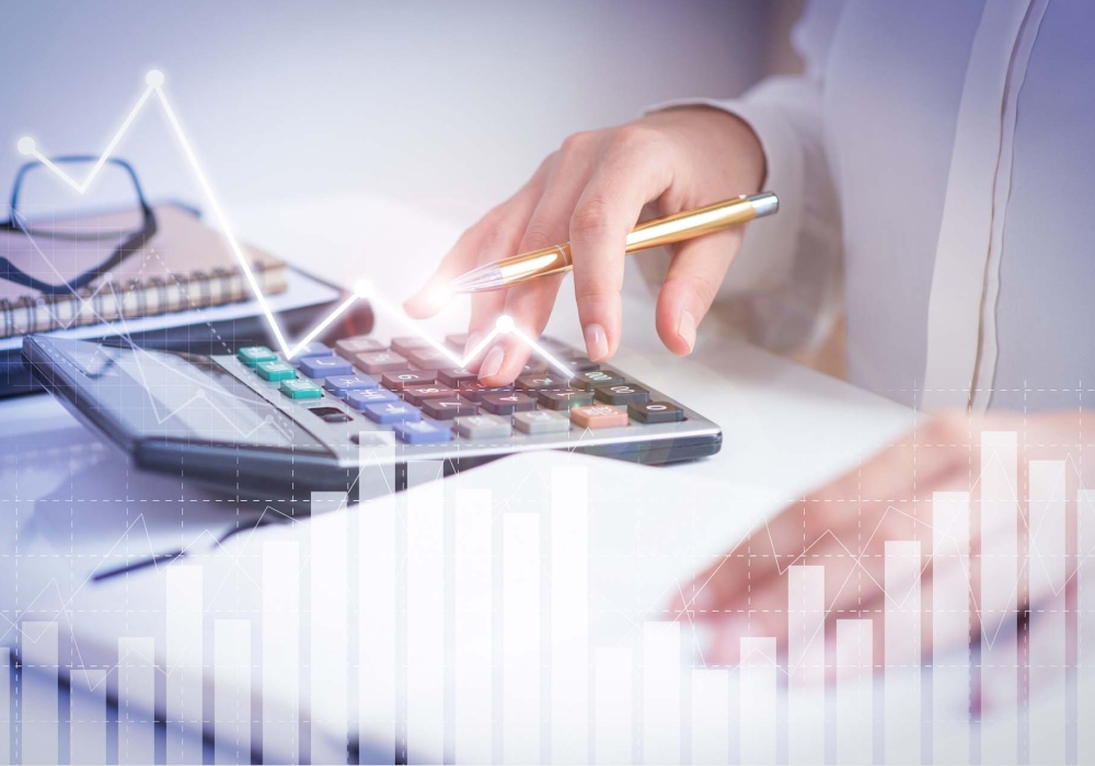 Accountant calculating profit with financial analysis graphs. Notebook, glasses and calculator lying on desk. Accountancy concept. Cropped view.